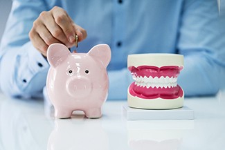 A jaw mockup sitting next to a man inserting a coin into a piggy bank