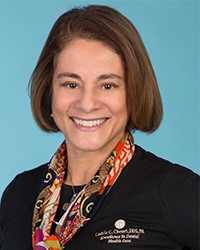 Short haired woman wearing a scarf and black scrubs