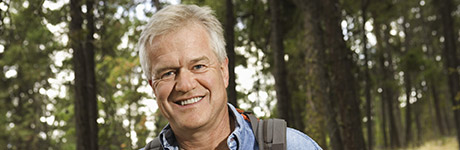 Older man wearing a backpack smiling