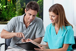 A dentist showing a female patient her digital impression on the screen and which tooth will receive a new crown