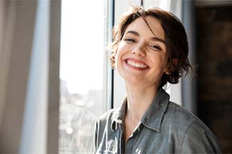 Woman with dental implants in Melbourne, FL smiling by window