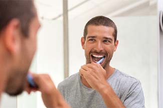 Man with dental implants in Melbourne, FL brushing his teeth