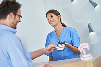 Patient smiling while paying for SureSmile in Melbourne
