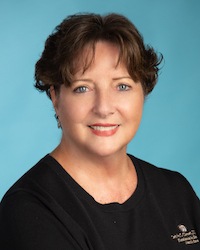 woman with dark short hair wearing black scrubs