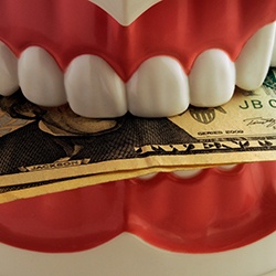 a model of a mouth biting down on cash