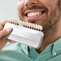 a dentist holding up a shade chart to a patient’s mouth