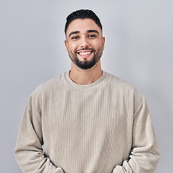 a smiling man wearing a tan shirt