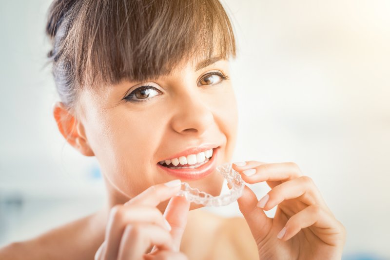 Woman putting on her Invisalign aligners 