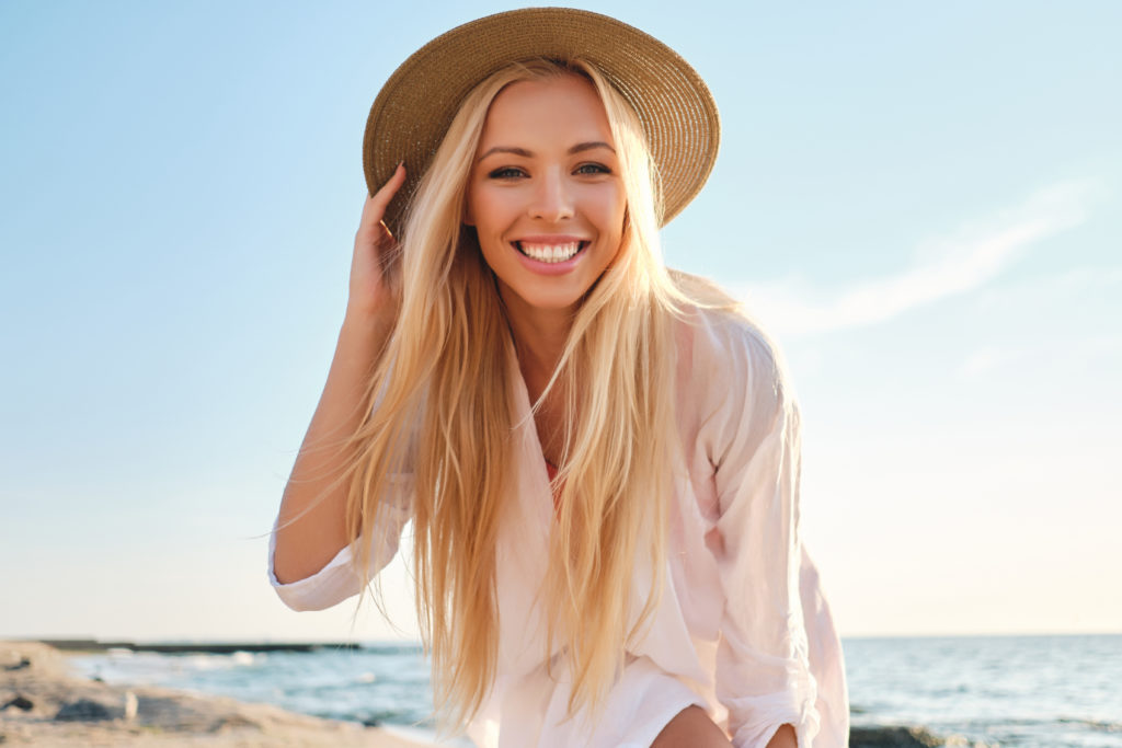 Woman with white, straight teeth smiling on the beach