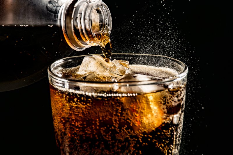 dark soda being poured into a glass