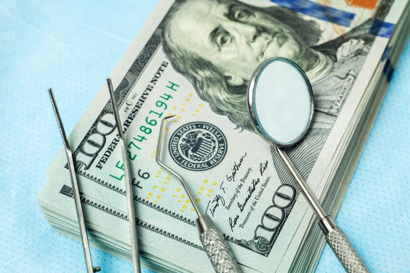 Dental tools placed on a stack of dollar bills