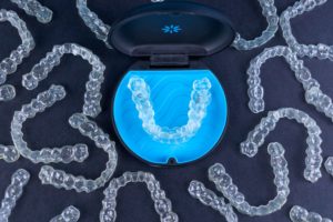 Birds eye view of a bunch of Invisalign trays on a dark background