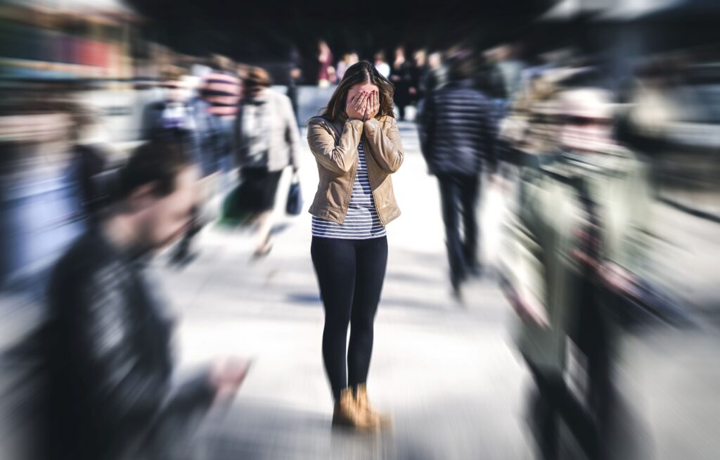 Woman in crowded street with hands over face